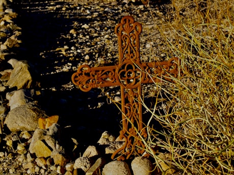 A man carrying a cross in a dry landscape.