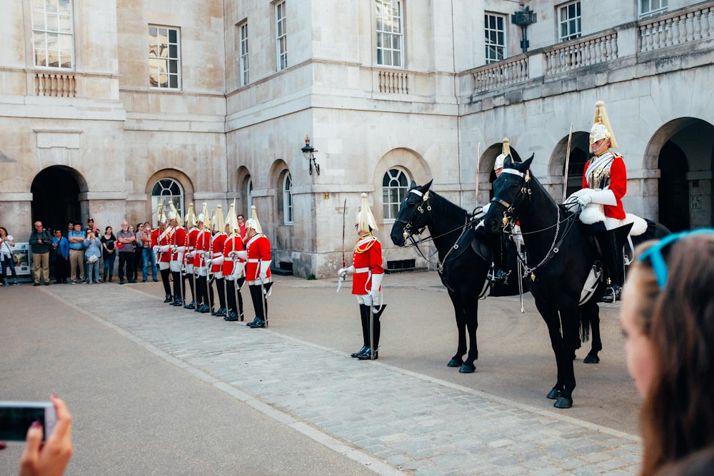 people in red and white uniform riding black horse during daytime