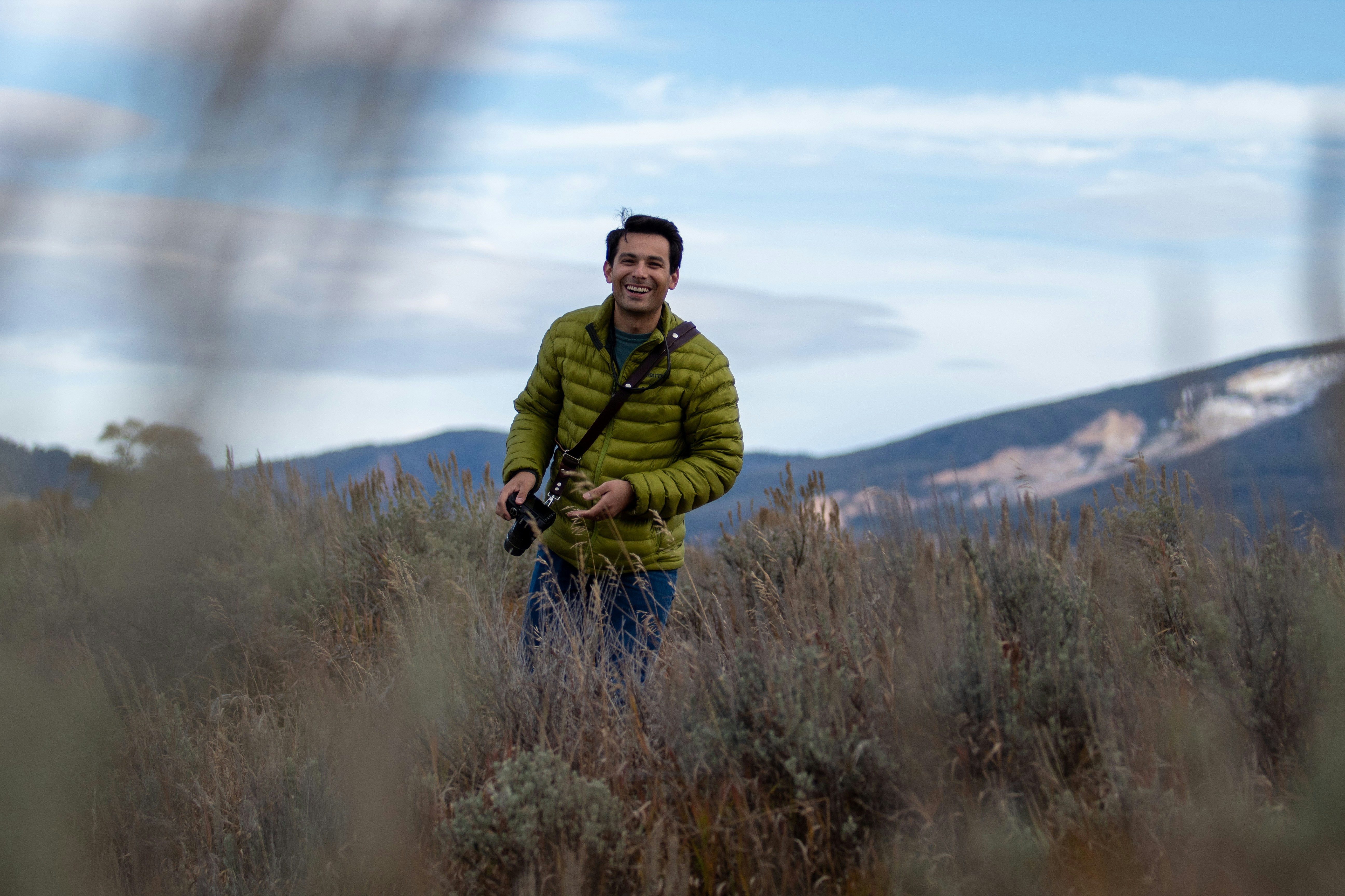Mann in grüner Jacke und blauer Jeans tagsüber auf braunem Rasen