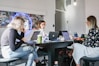 3 women sitting on chair in front of table with laptop computers