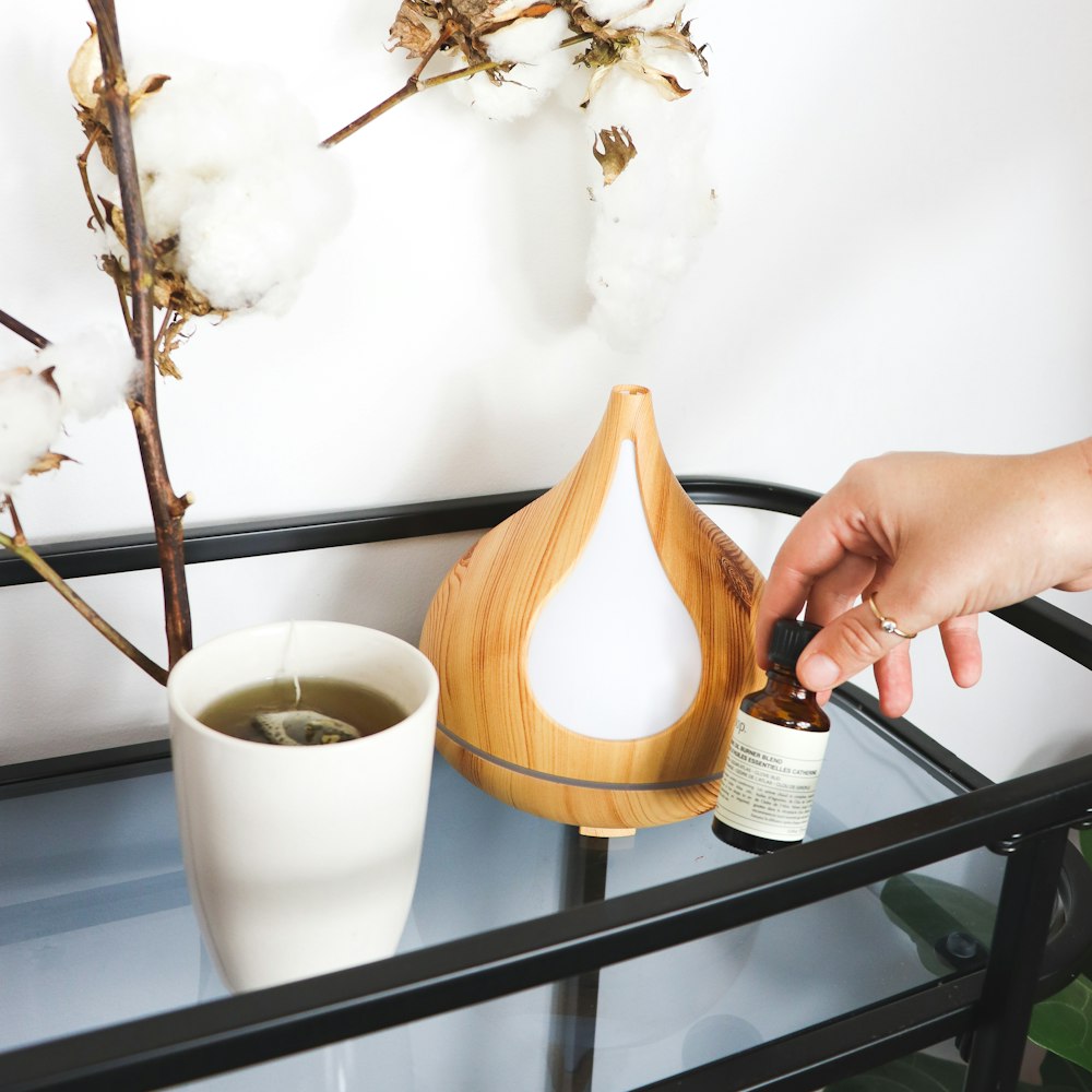 personne versant du lait sur une tasse en céramique blanche