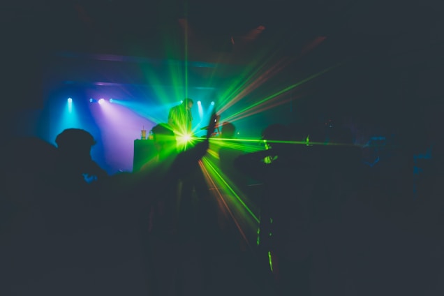 A vibrant club scene with colorful lights, dancing crowd, and a DJ energizing the room.