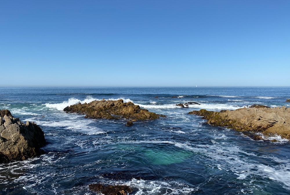 brown rock formation on sea under blue sky during daytime