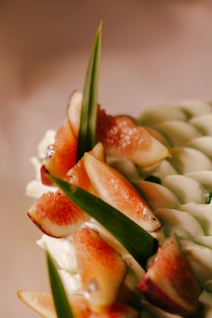 Elegant jar of fig jam surrounded by fresh figs and green leaves on a cream cloth.