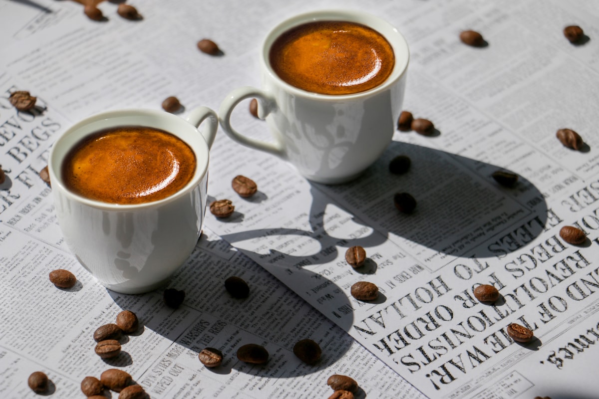 Two Cups of Fresh Espresso Coffee sitting on a Newspaper