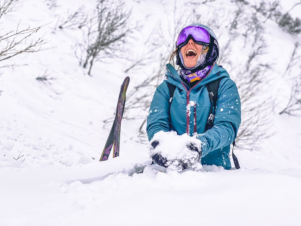 person in blue jacket and blue pants holding black and brown snow ski blades on snow