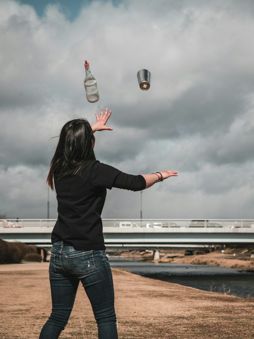 woman in black long sleeve shirt and blue denim jeans holding clear plastic bottle