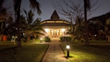 Evening shot of a beautifully lit tropical home with palm trees swaying gently.