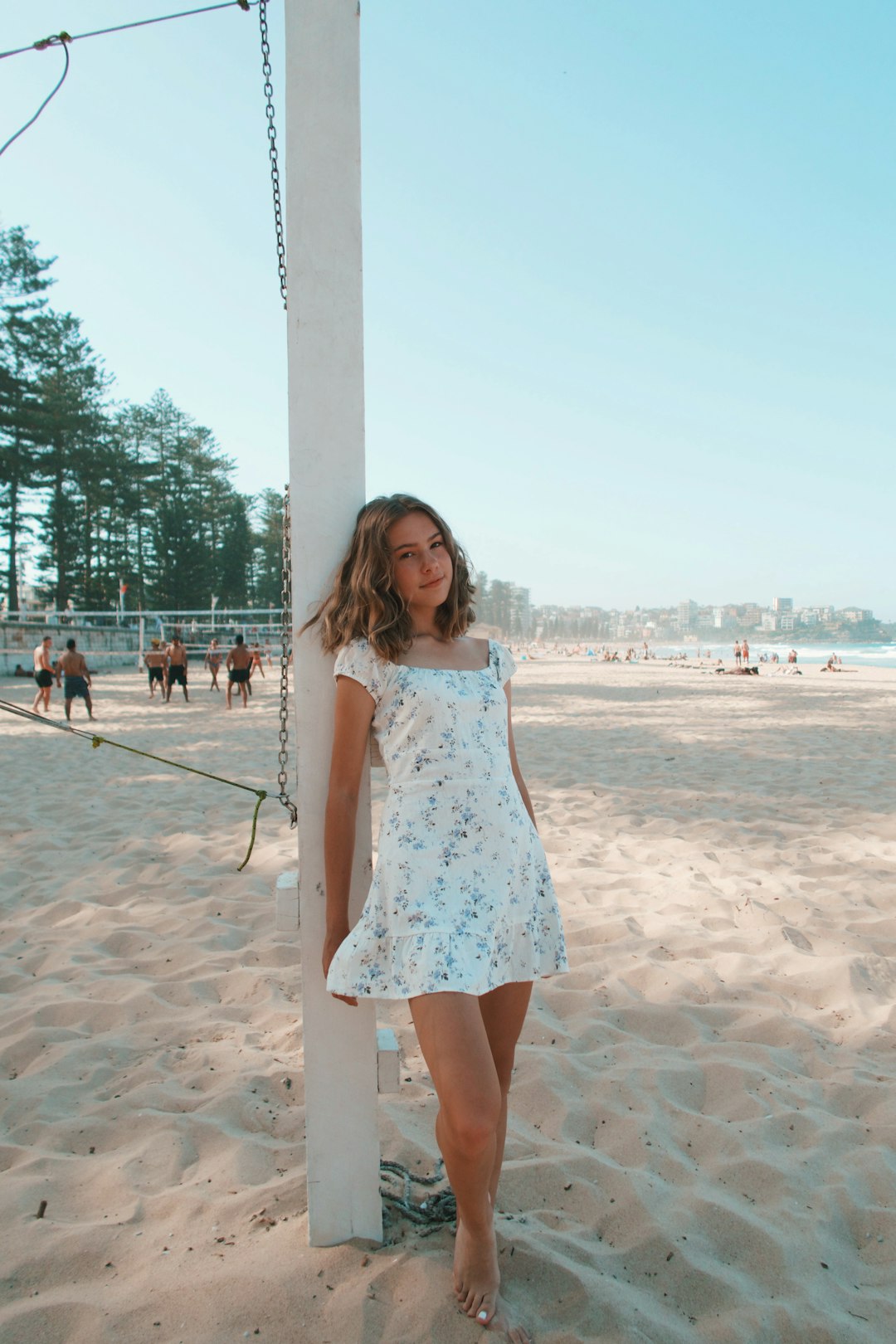 woman in white and blue floral tank dress standing on beach during daytime