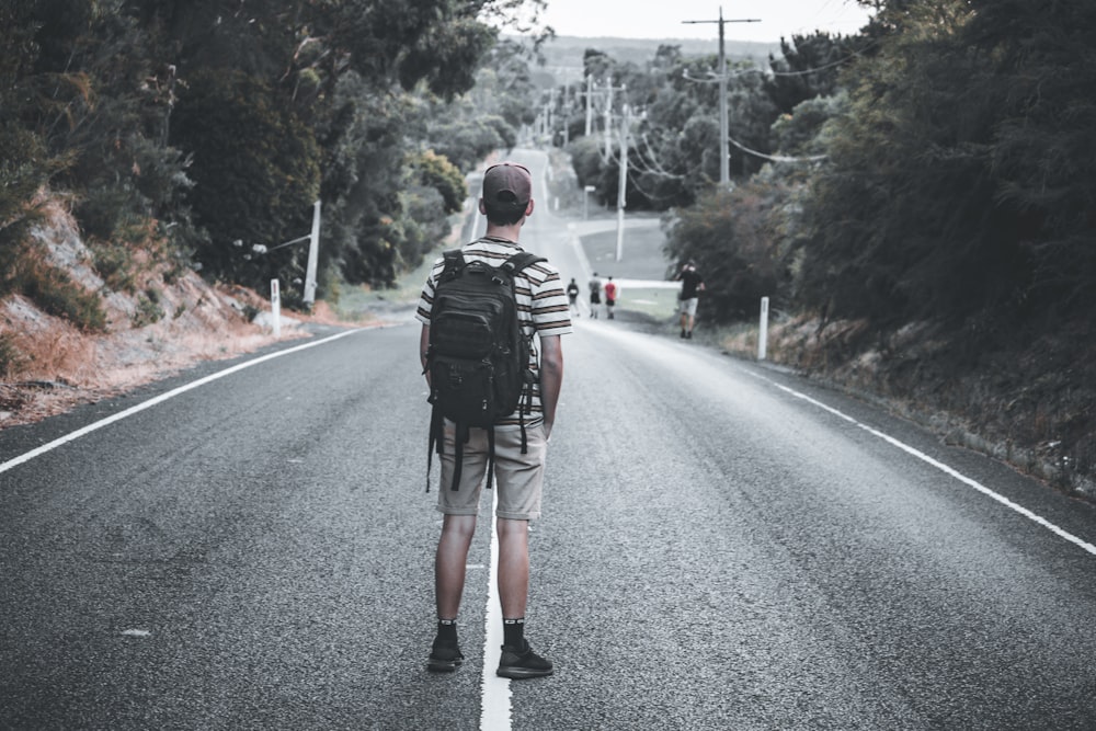 man in black jacket and black backpack walking on road during daytime