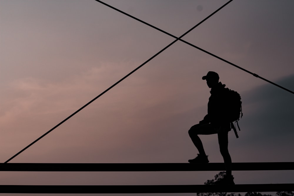 silhouette d’homme grimpant sur la corde pendant le coucher du soleil