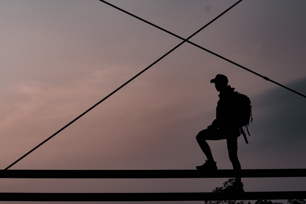 silhouette of man climbing on rope during sunset