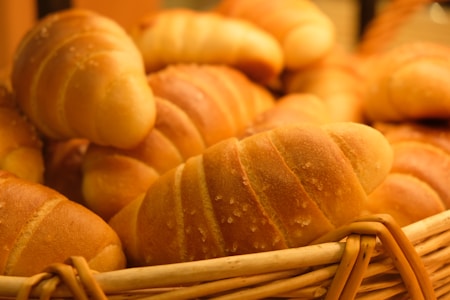 A basket full of freshly baked croissants with a golden-brown crust and flaky texture. The image highlights the warm and inviting look of the pastries, arranged closely together.