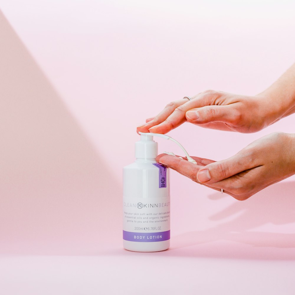 person holding white and purple plastic bottle