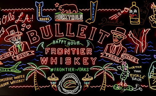 A vibrant neon art piece featuring a variety of colorful, stylized characters and text related to whiskey, cocktails, and nightlife. Key elements include a skeleton in a top hat labeled 'Old Soul,' a man in a hat with sunglasses labeled 'Fresh Times,' palm trees, and playful phrases like 'Watch Your Pickle Back' and 'Conserve Water Drink Whiskey.' Various neon symbols such as bottles, glasses, and drink-related imagery make up the scenery.