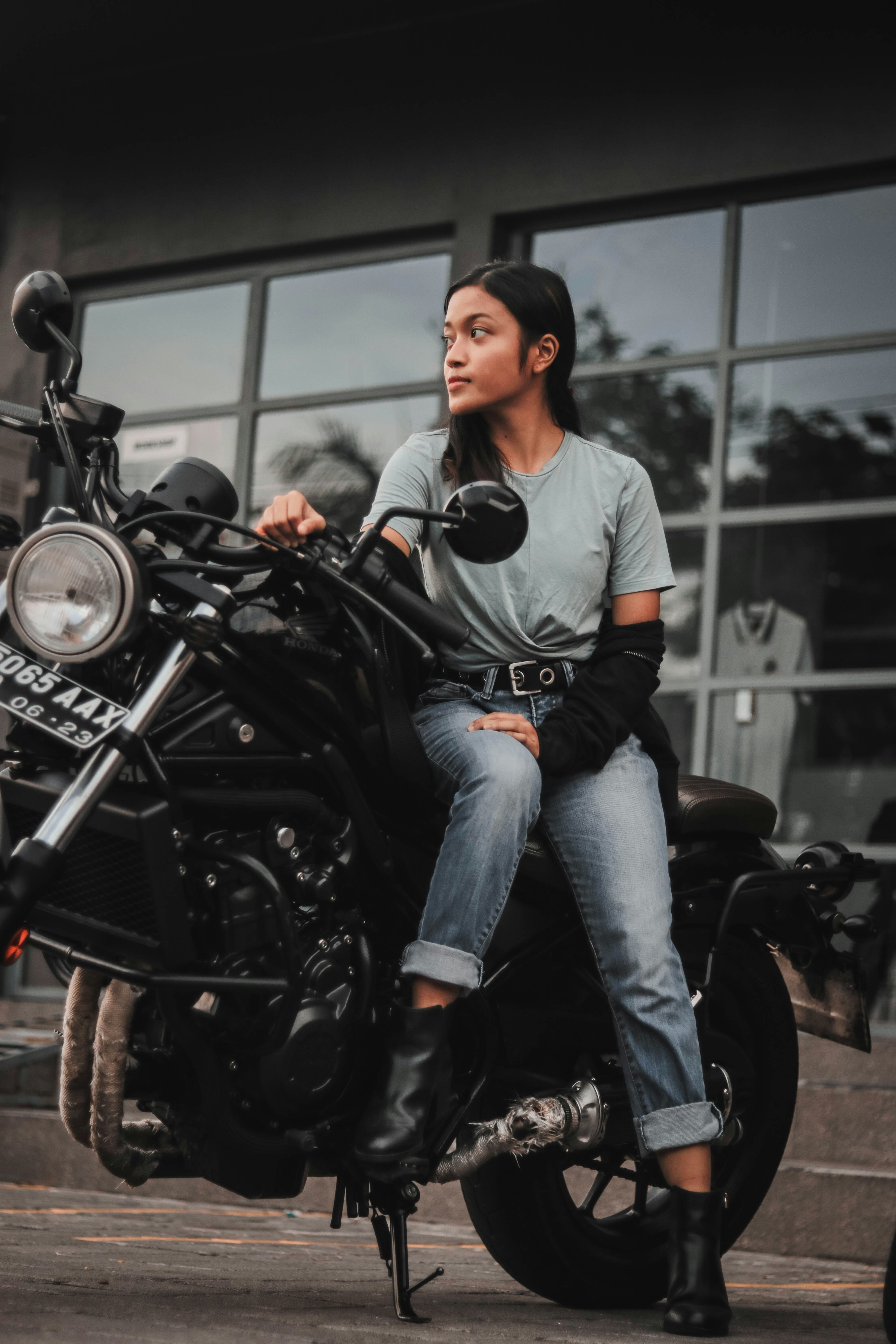 A woman sitting on a motorcycle in front of a building
