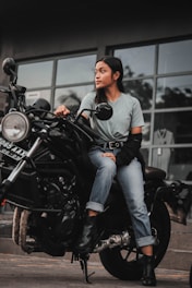 A woman sitting on a motorcycle in front of a building