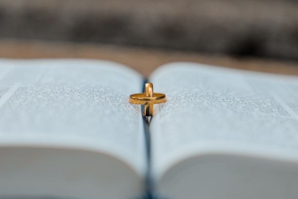 A close-up of a wedding ring resting on an open book, symbolizing love and commitment.