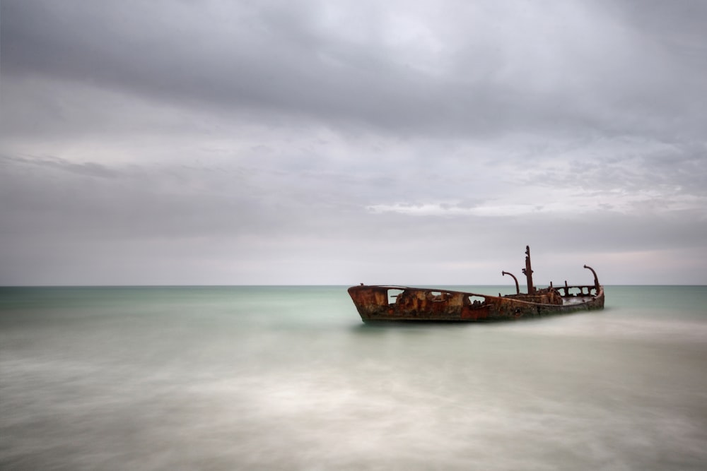 brown ship on sea under cloudy sky during daytime