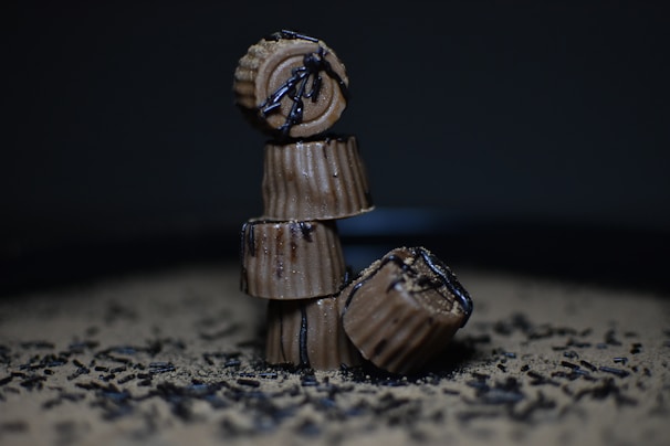 A playful stack of chocolate brigadeiro cake cups with glossy ganache topping and sprinkles.