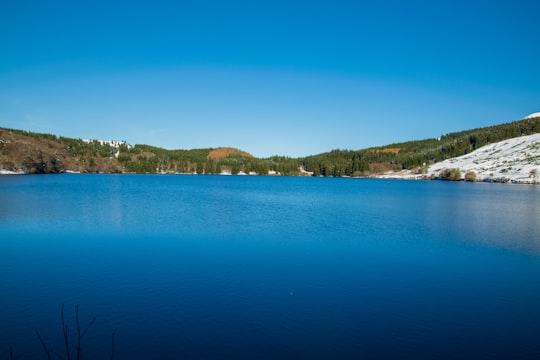 blue body of water near green trees during daytime in Lac de Guéry France