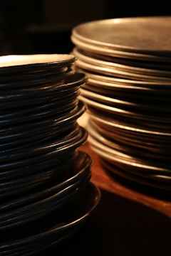 Stacks of polished copper sheets and metal rods gleaming under warm lighting in a modern warehouse.