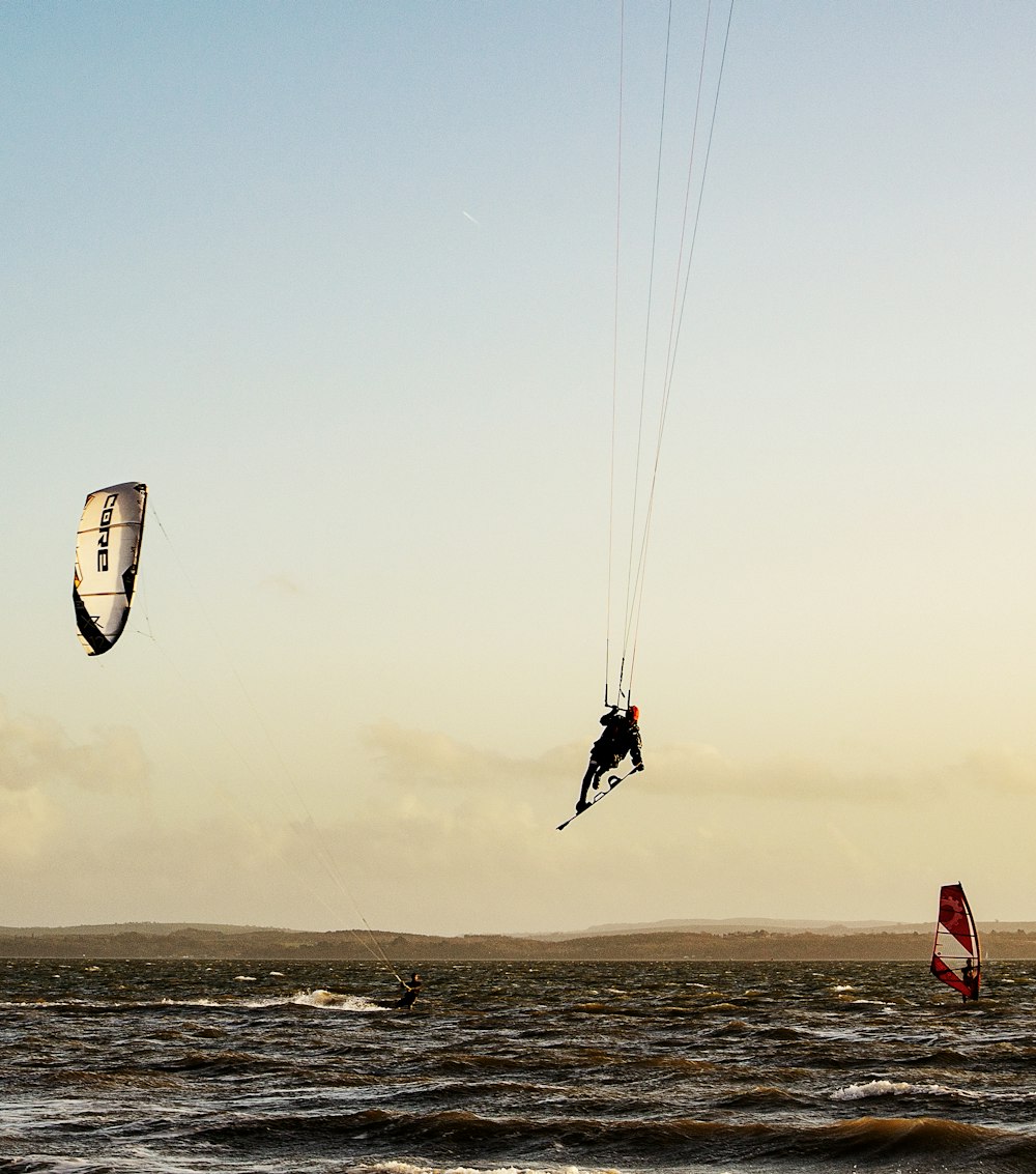 person in red shirt and black shorts riding on white and red parachute during daytime