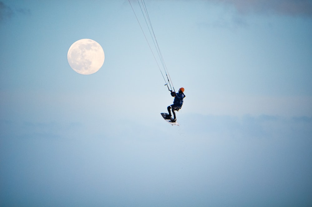 man in black jacket and black pants riding on black and yellow parachute under white clouds