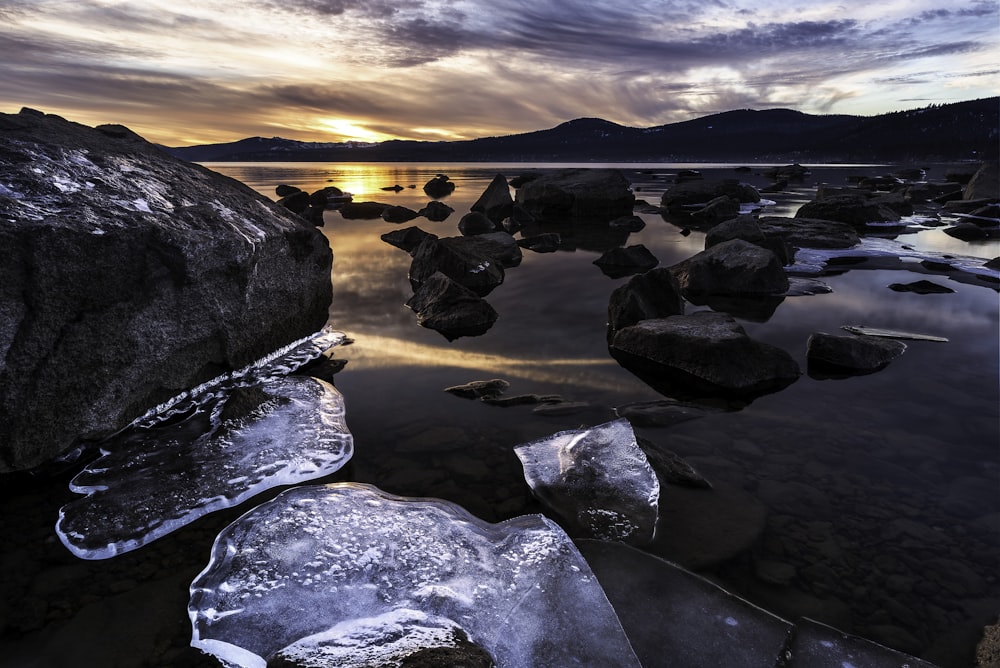 gray rocks on body of water during sunset