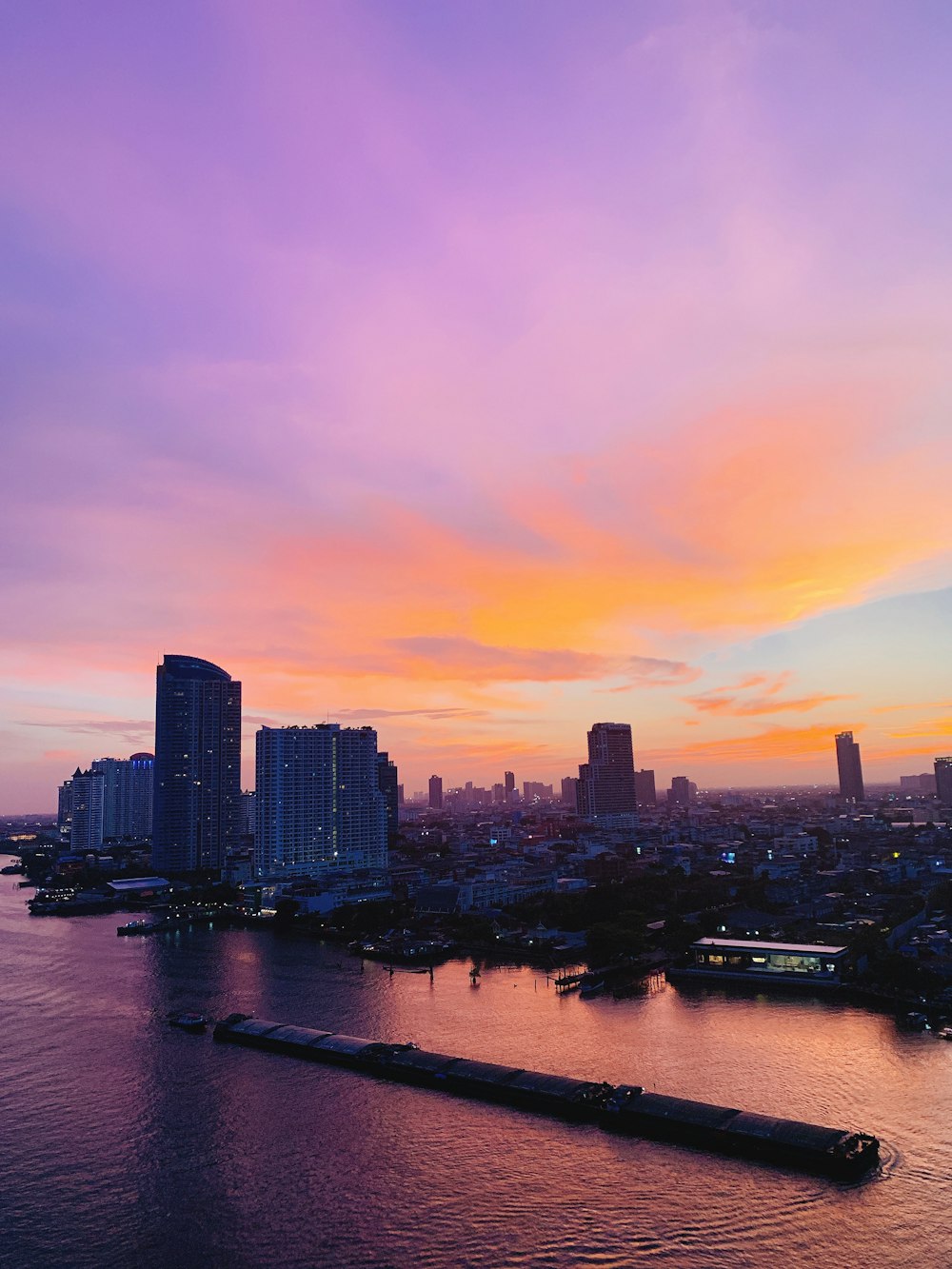 city skyline across body of water during sunset