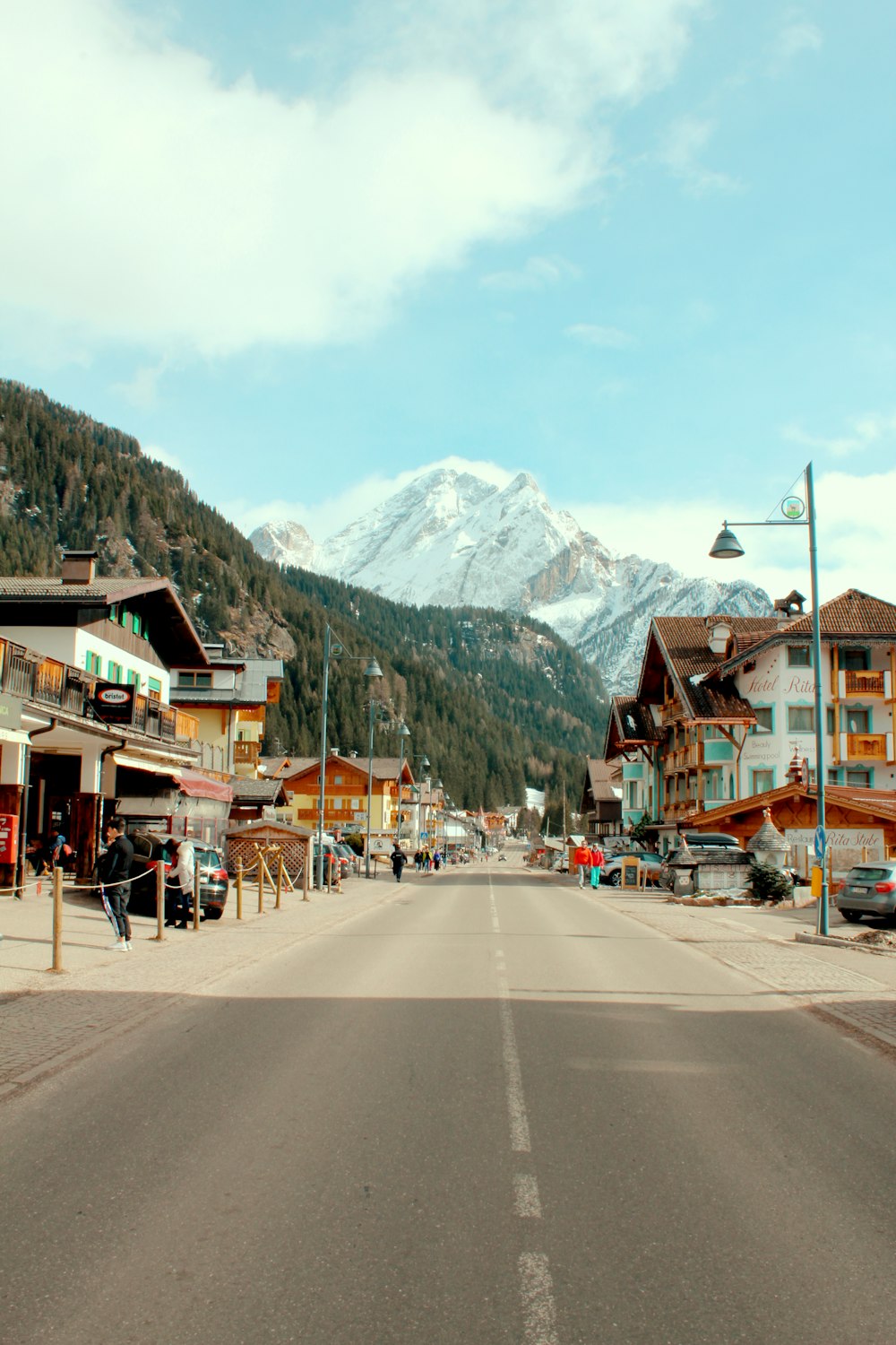 gray asphalt road near houses and mountain range during daytime