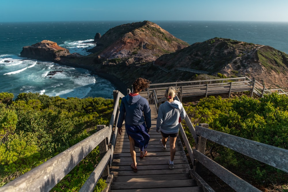 man and woman walking on wooden bridge