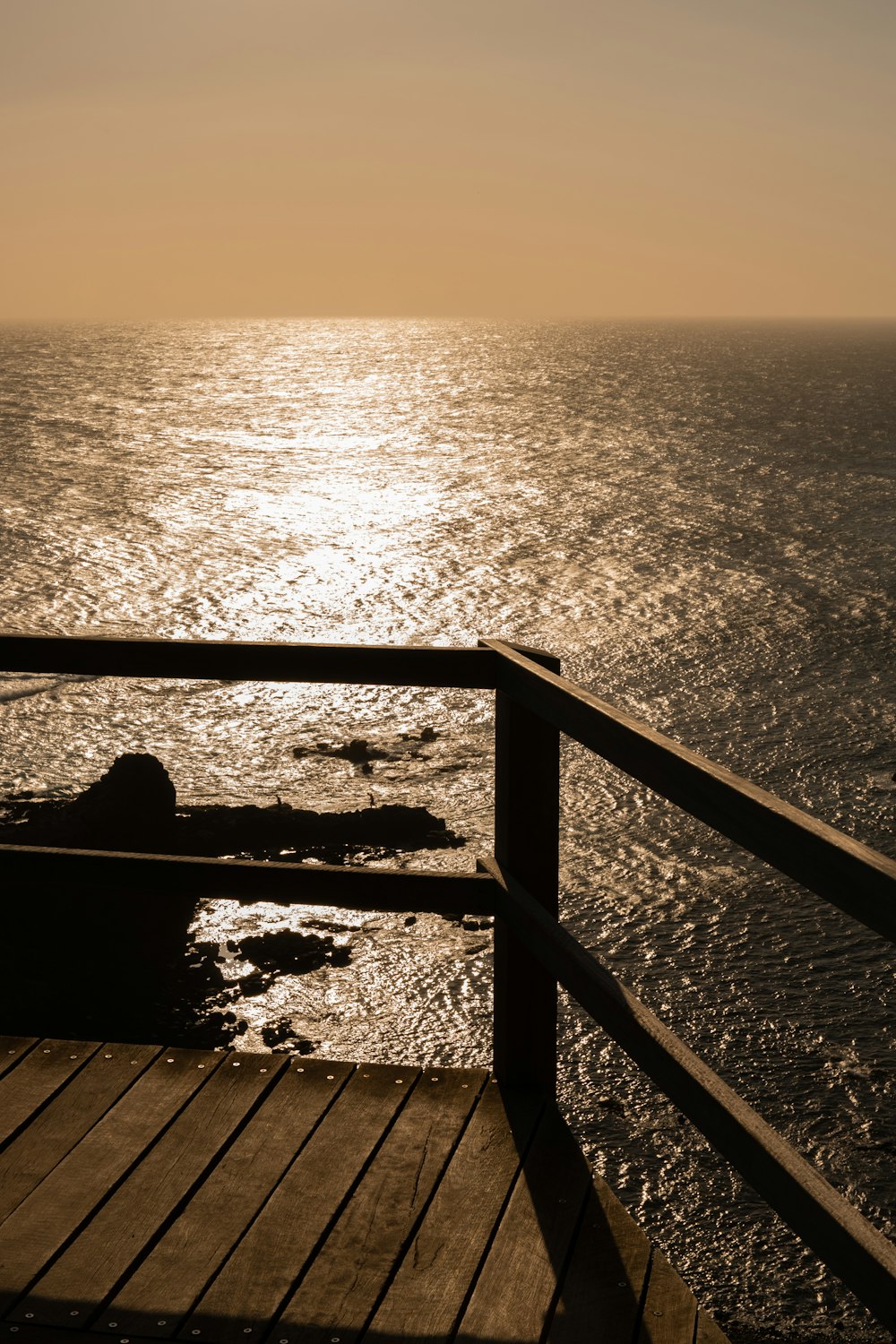 silhouette of person sitting on stairs near body of water during daytime
