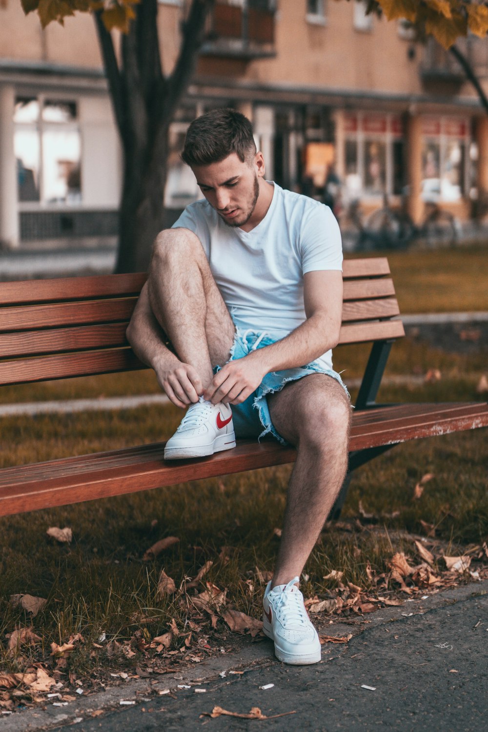 man in gray crew neck t-shirt sitting on brown wooden bench during daytime