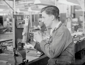 A technician adjusting settings on a roll forming machine in a workshop.