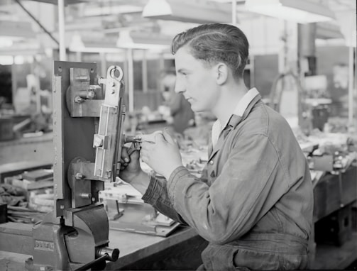 An instructor guiding students through machinery operation in a technical workshop.