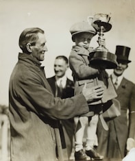 A young child holding a trophy with family, preserving family history through storytelling