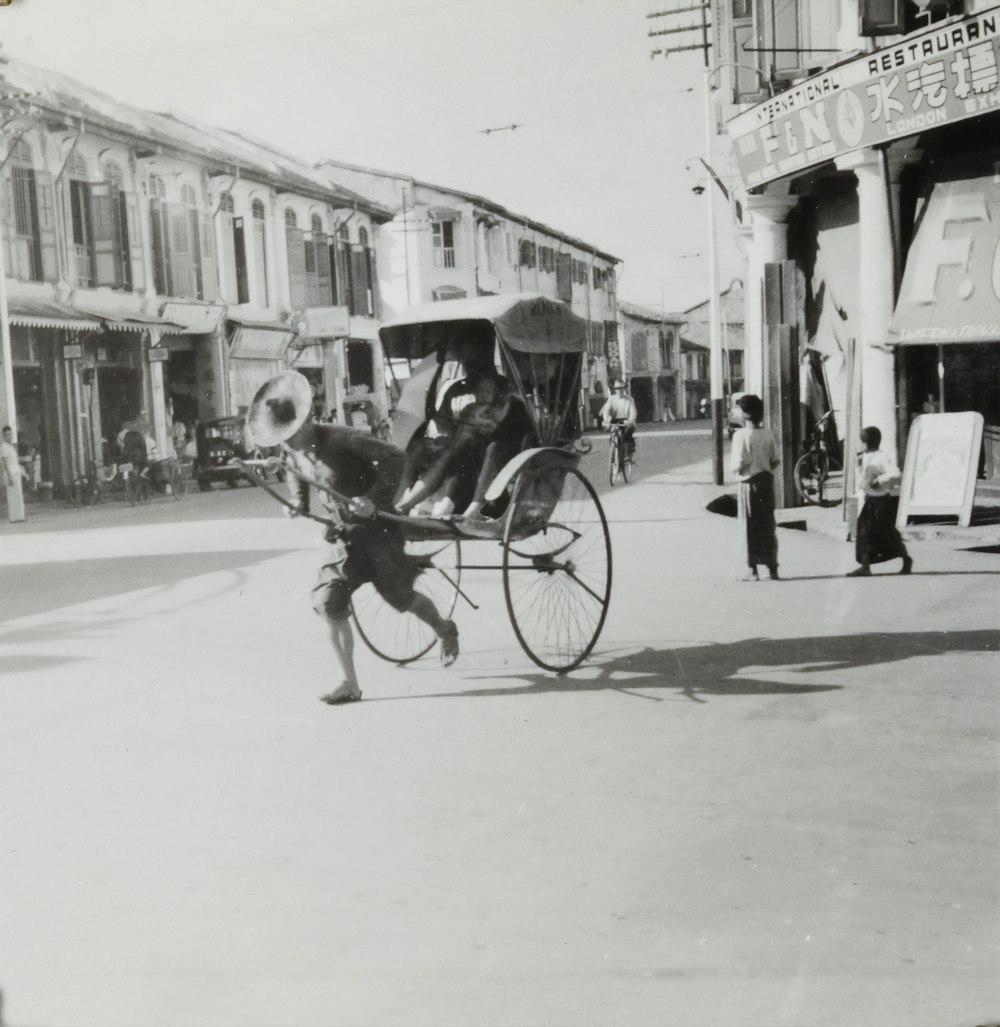 grayscale photo of man riding on horse carriage in the street