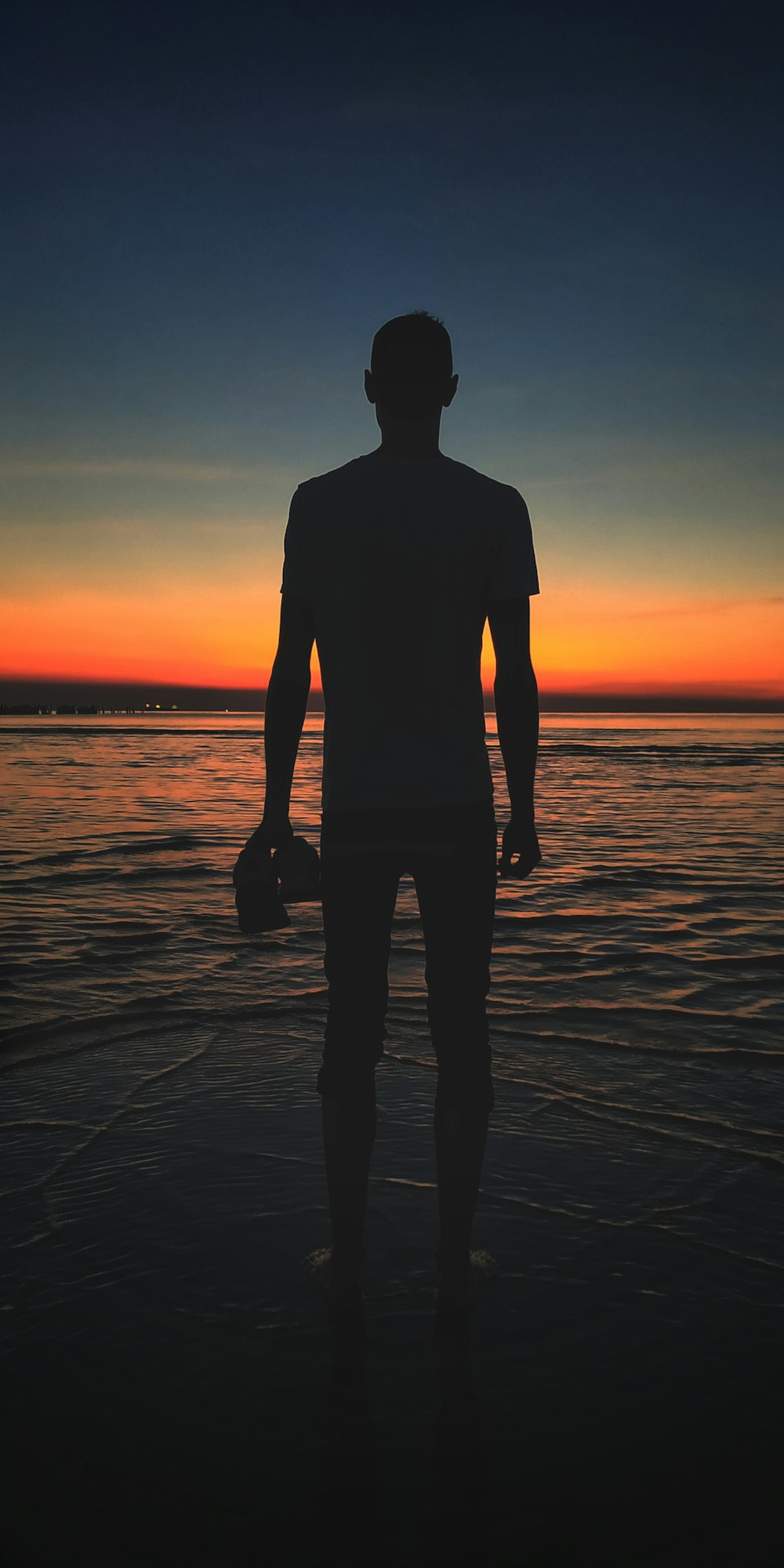 silhouette of man standing on beach during sunset