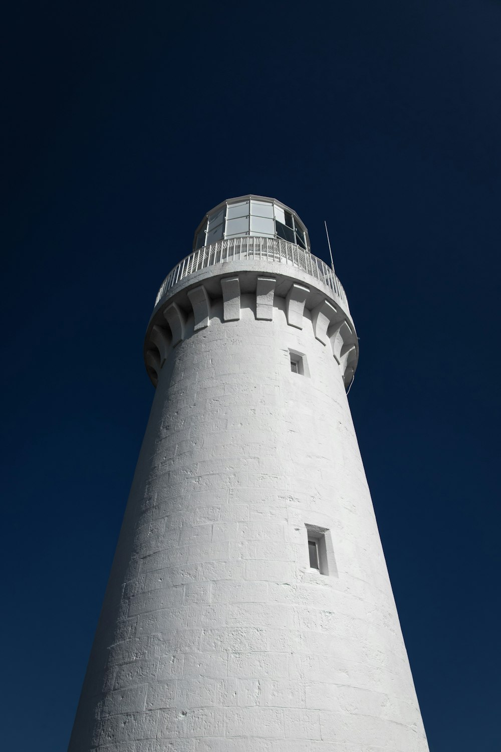 Faro in cemento bianco e nero sotto il cielo blu durante il giorno