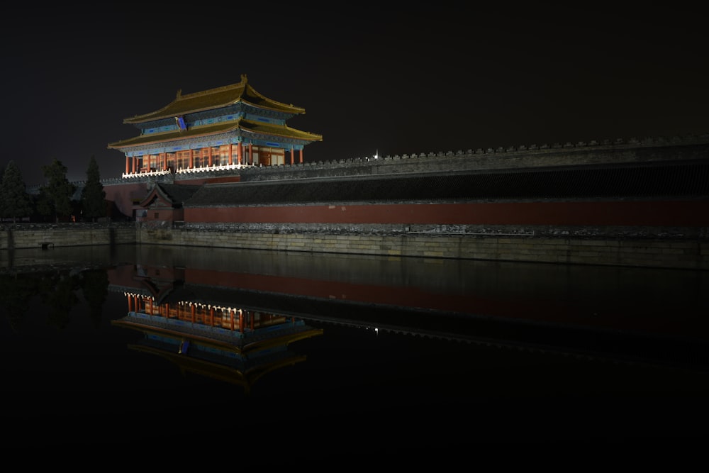 brown and white temple near body of water during night time