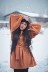 woman in brown coat and brown knit cap standing on snow covered ground during daytime