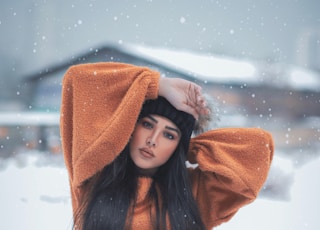 woman in brown coat and brown knit cap standing on snow covered ground during daytime