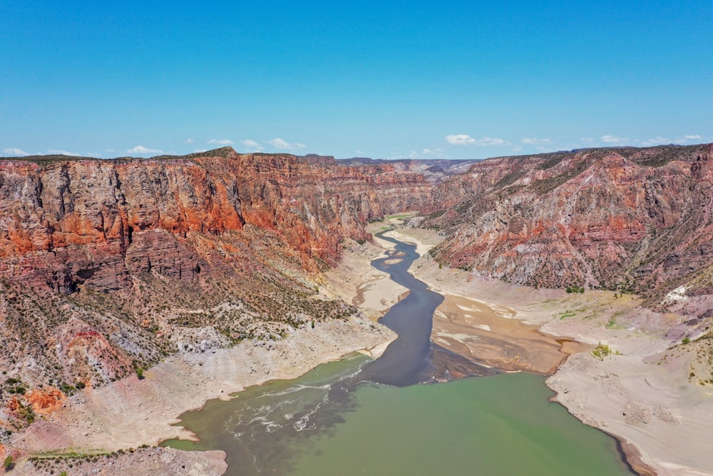 brown rocky mountain beside river under blue sky during daytime