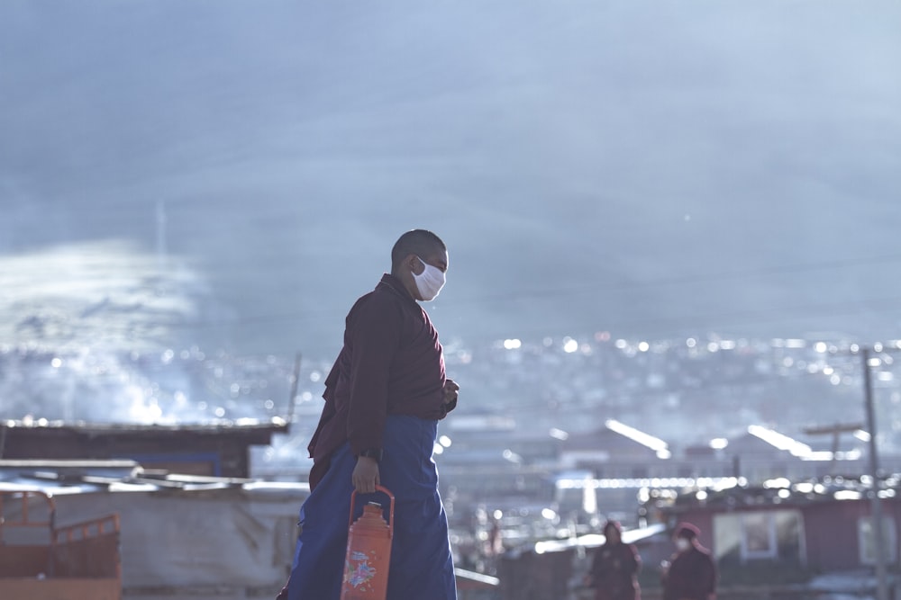 man in black coat and orange pants standing on the roof during daytime