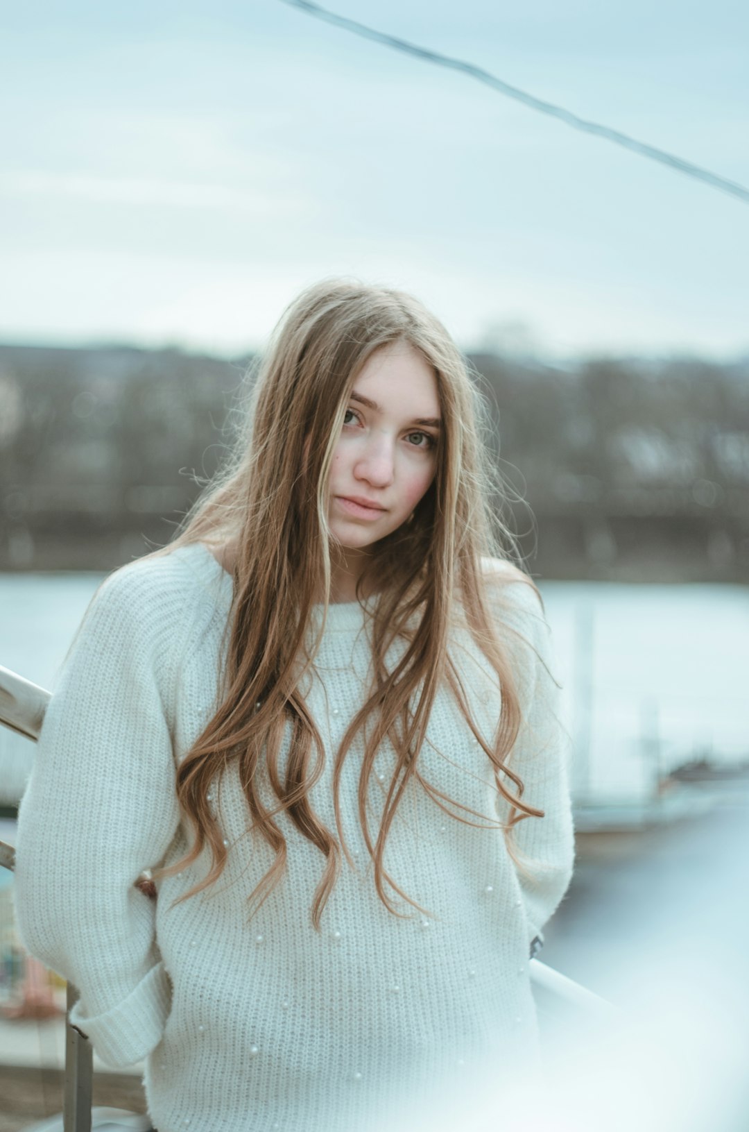 woman in white sweater standing near body of water during daytime