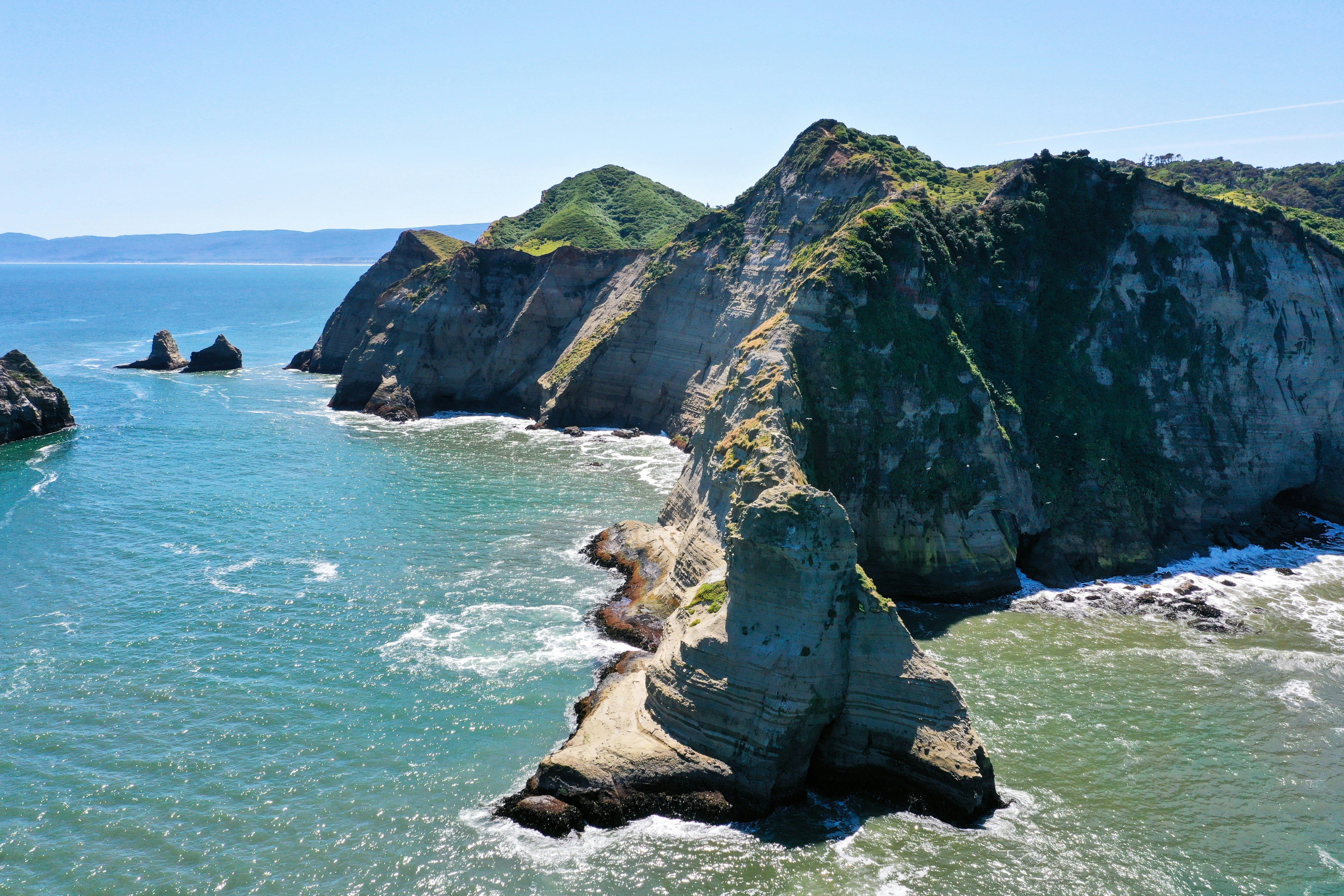 brown and green rock formation on sea during daytime