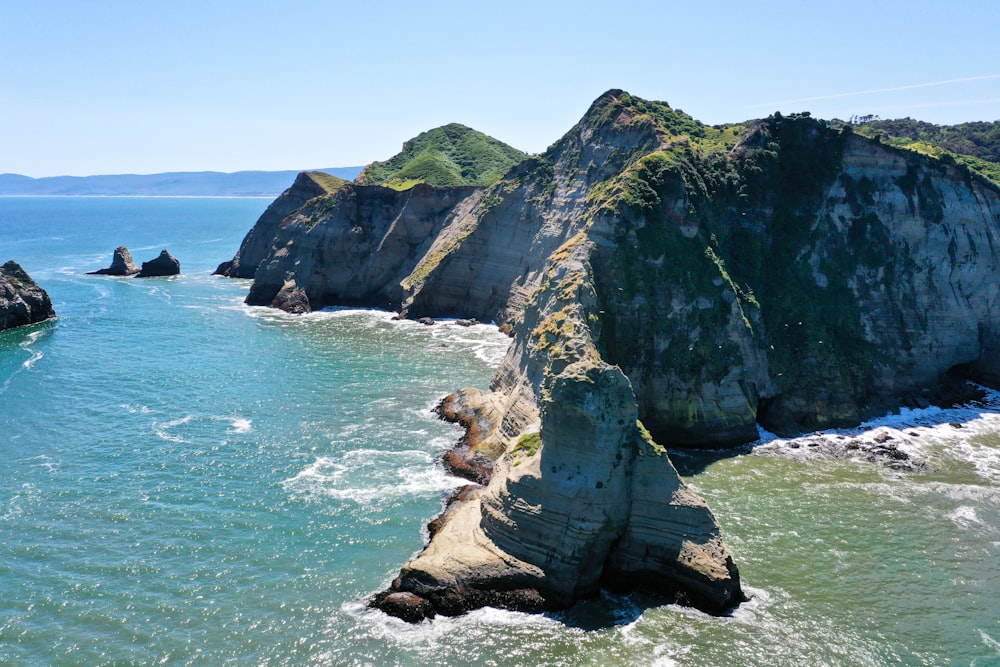 brown and green rock formation on sea during daytime