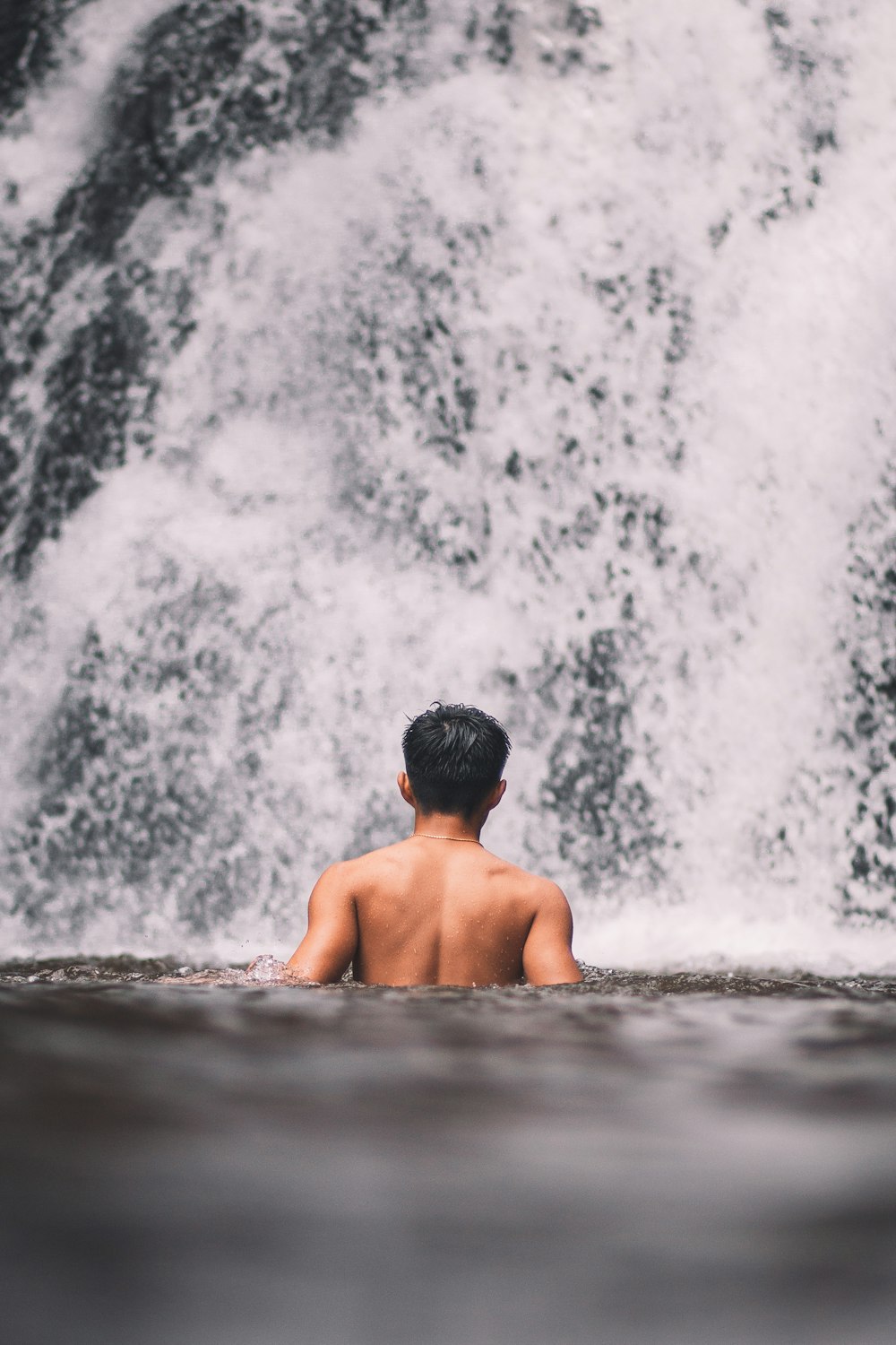 man in water falls during daytime