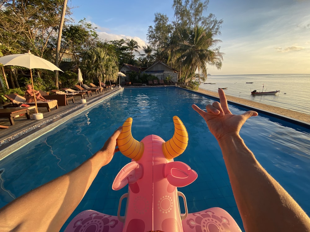 persona sdraiata sul galleggiante gonfiabile rosa sulla piscina durante il giorno